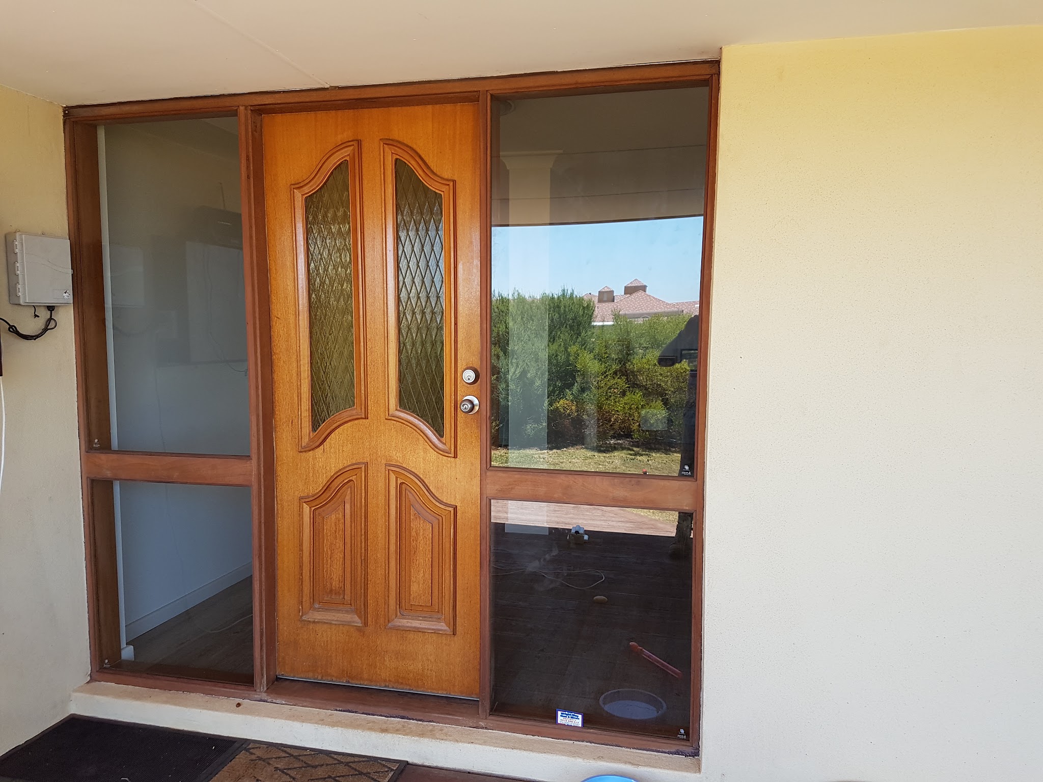 A front entry with a timber door flanked by full height fixed glass panels